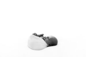 tiny newborn baby wrapped up and photographed into the light sleeping. Photographed by Bristol newborn photographer Melanie East